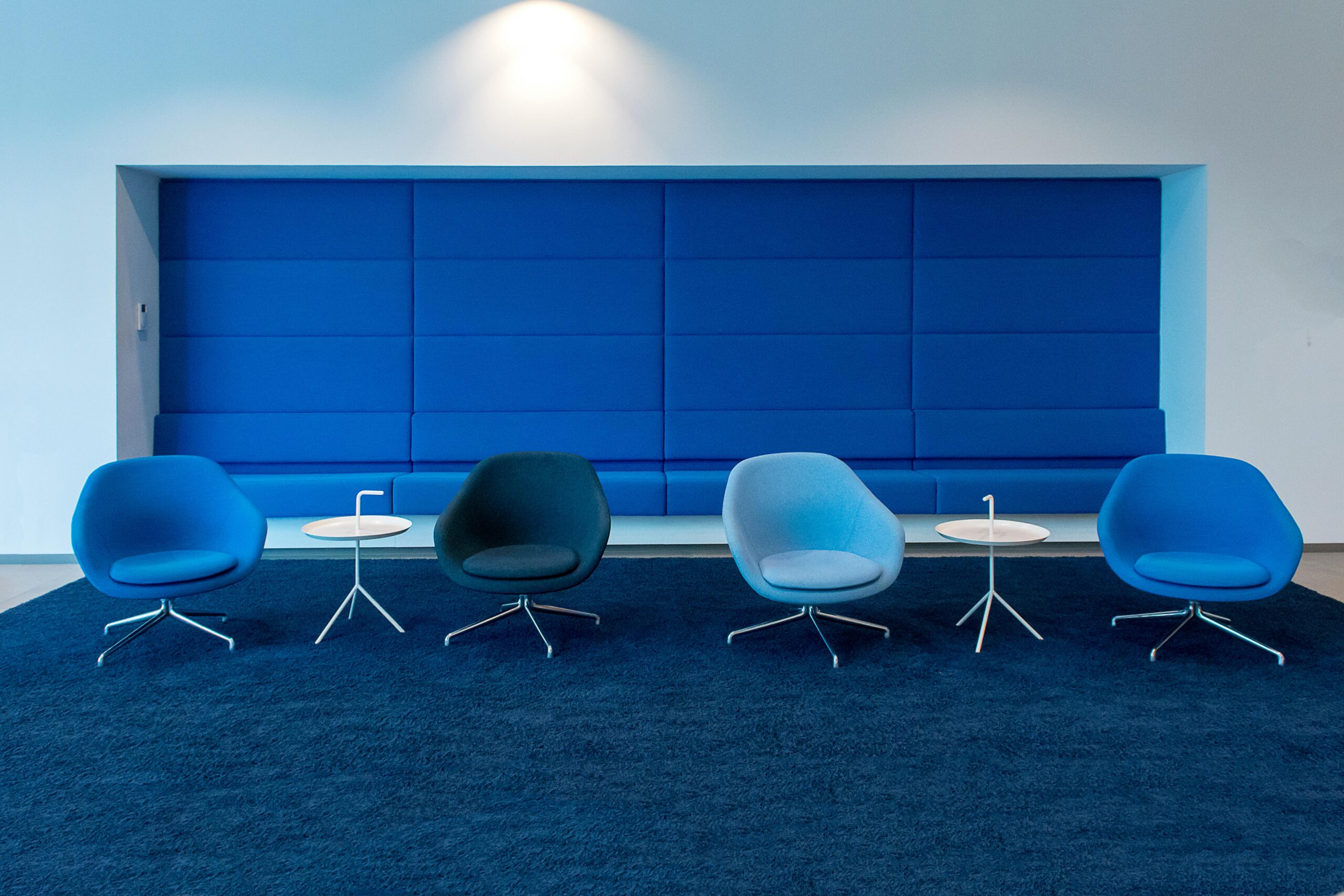 Contemporary office space featuring blue chairs and tables with a modern design.